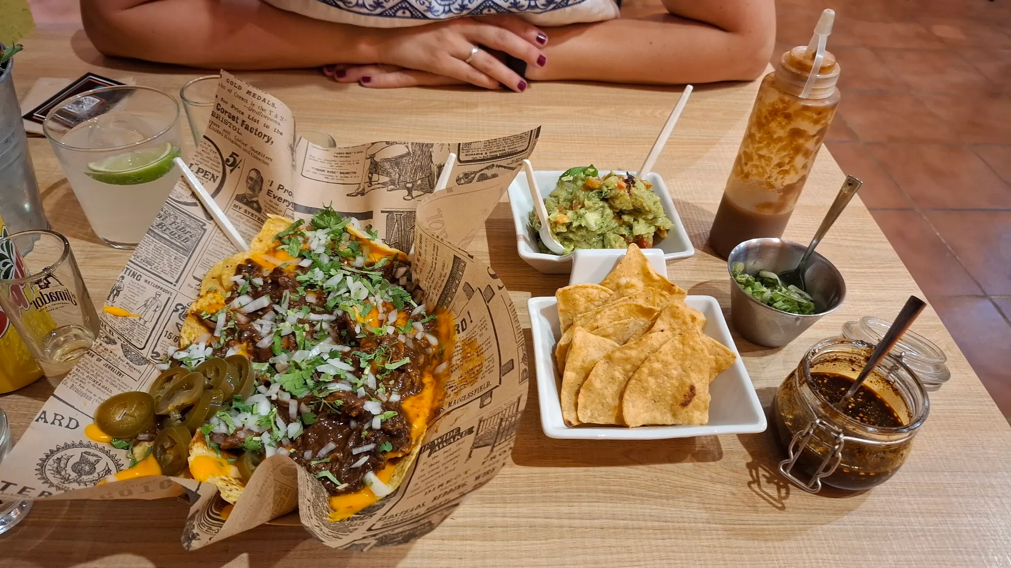 Una mesa con tacos, nachos y salsas para compartir