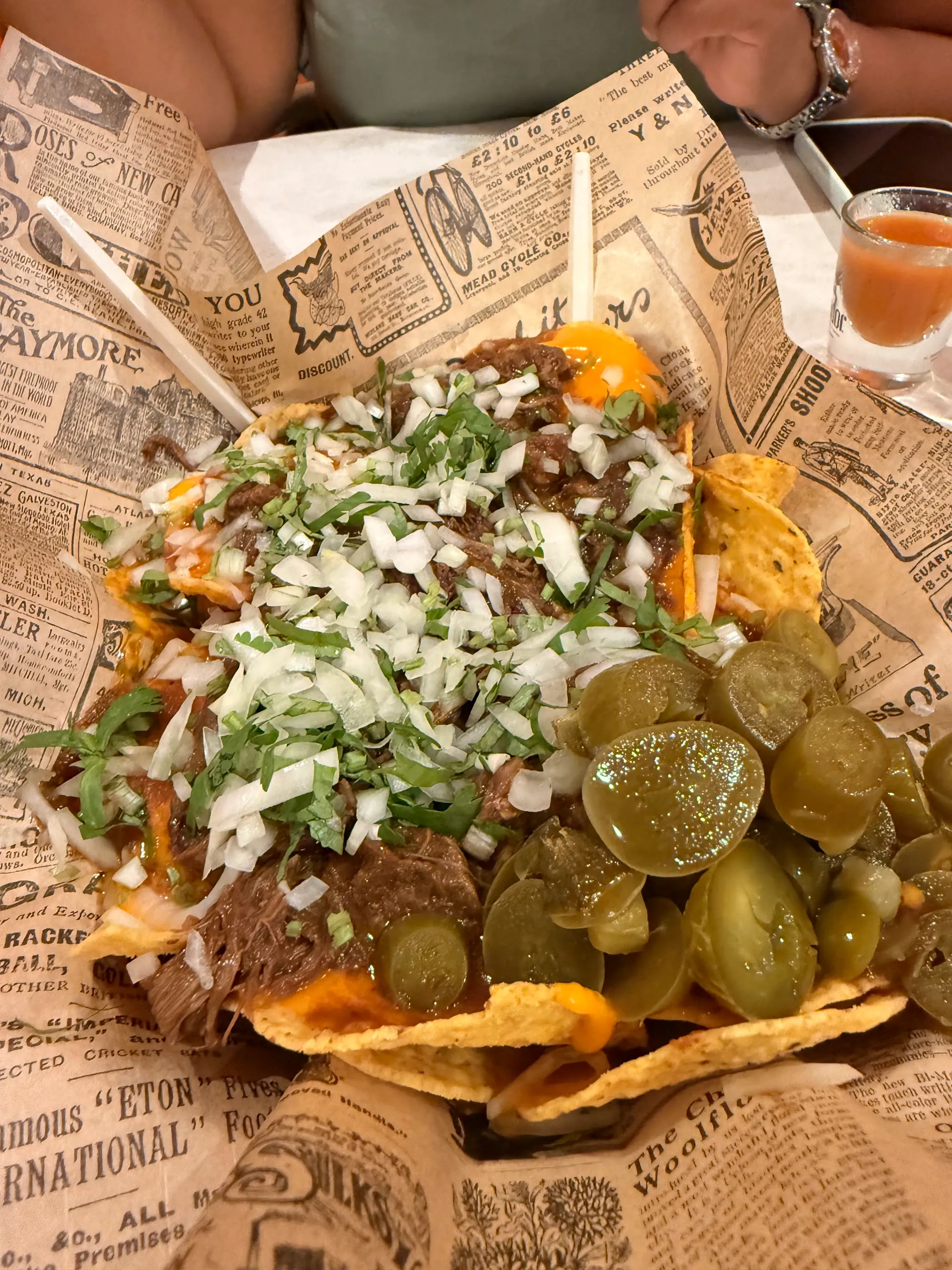 Nachos con carne, cebolla y jalapeños sobre papel de periódico