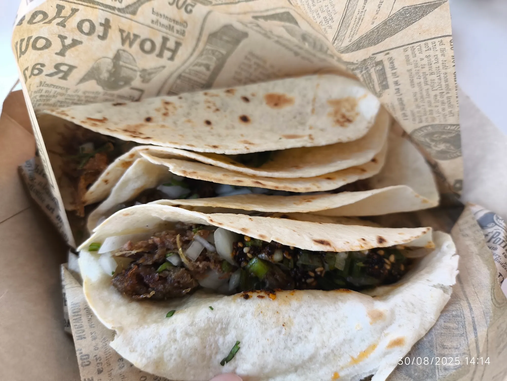 Tacos abiertos con carne guisada sobre papel de periódico